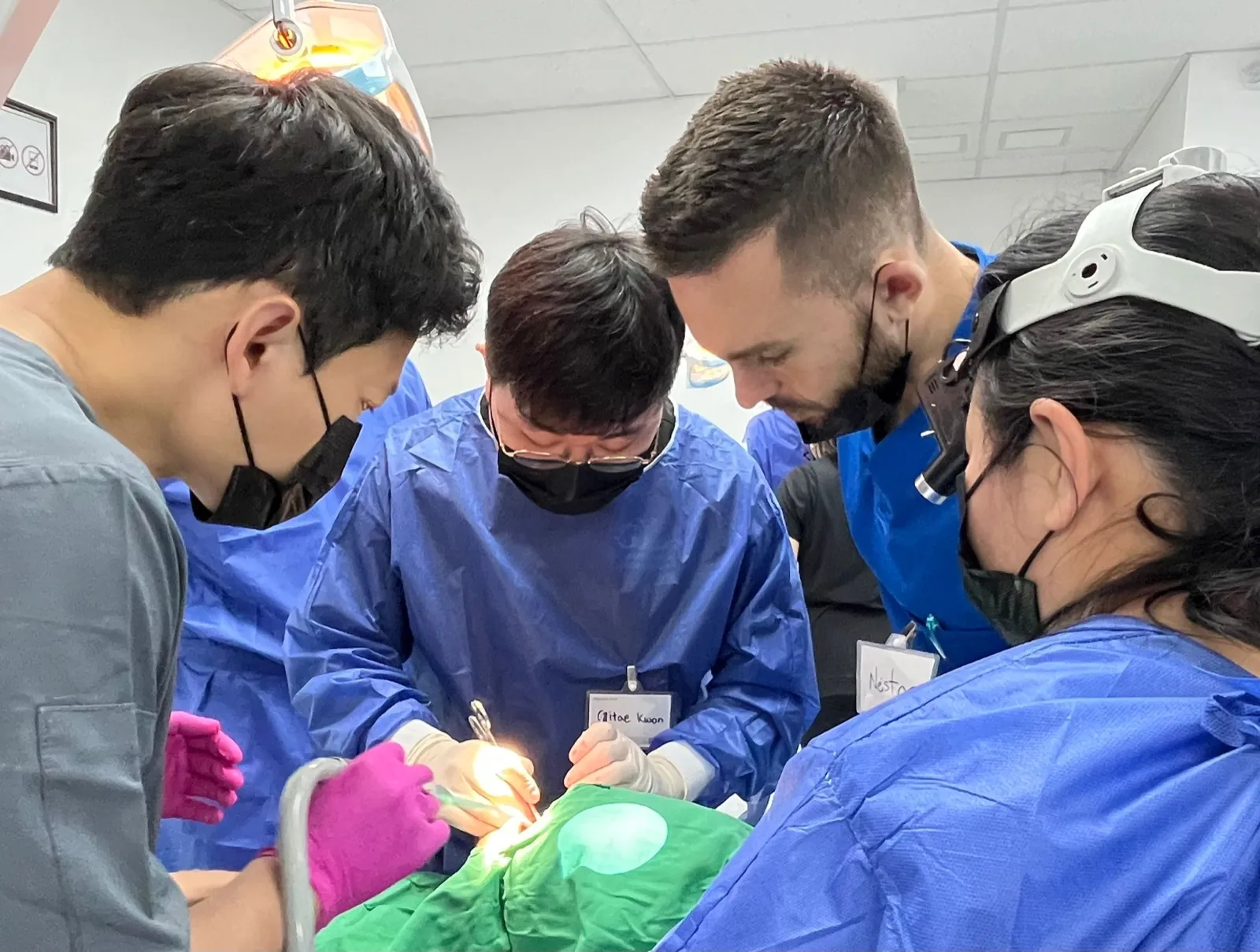 Dr. Kwon performing implant surgery as dentists watch closely