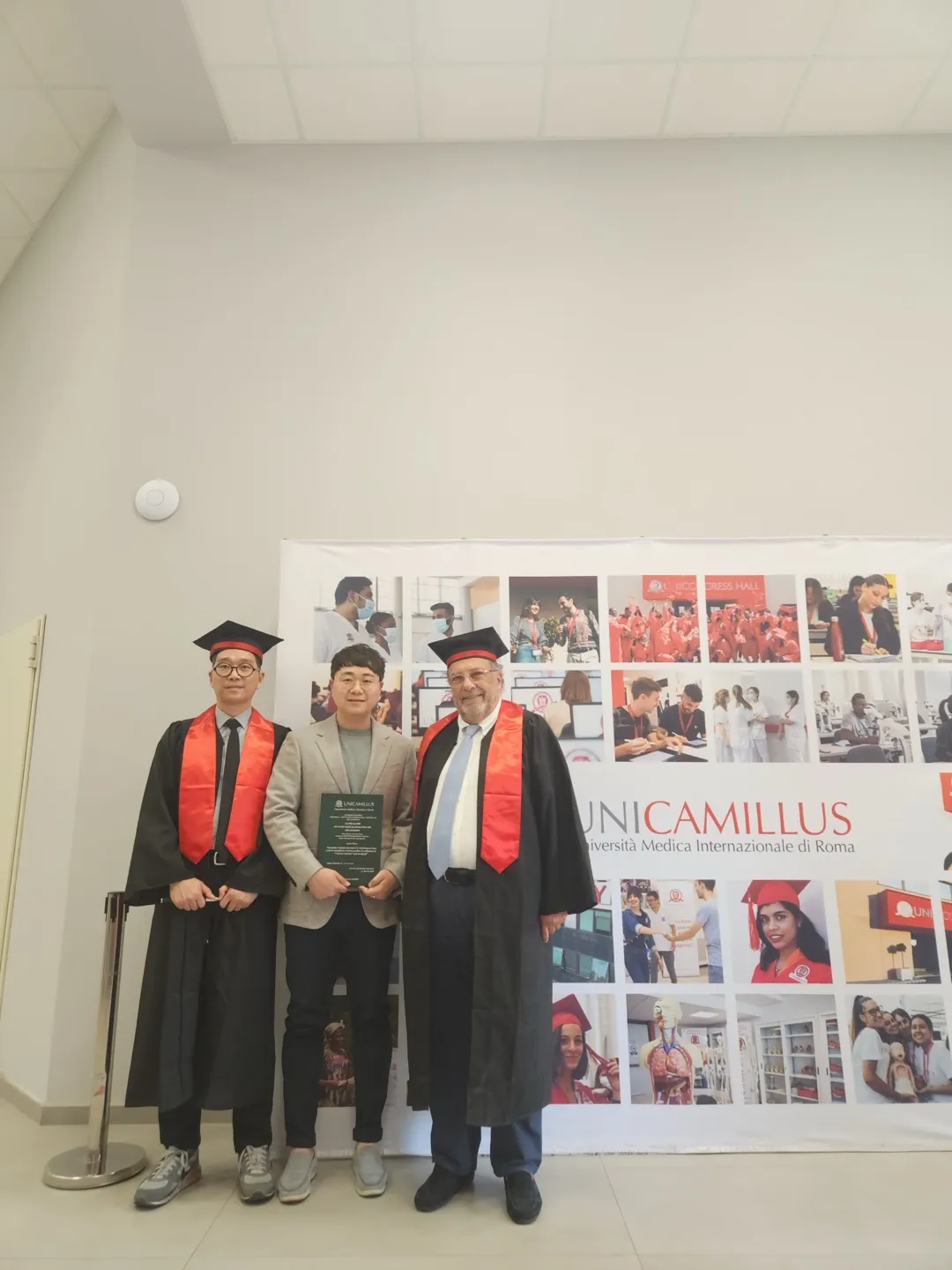 Dr. Kwon at UniCamillus in Rome with two colleagues in academic gowns