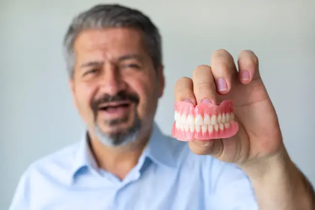 a man is holding a denture in his hand .