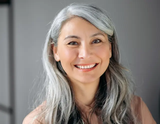 a woman with gray hair is smiling for the camera .